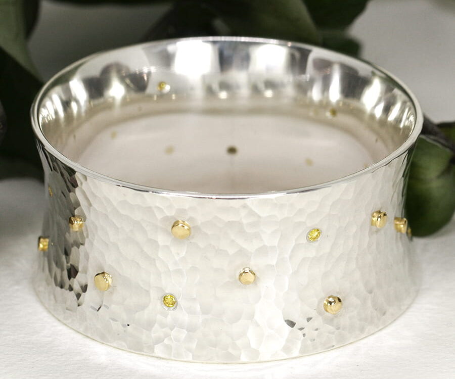 18. 'Guinivere', Sterling Silver bangle with 15 18ct Yellow gold Rivets and eight 10pt Fancy Yellow Diamonds
